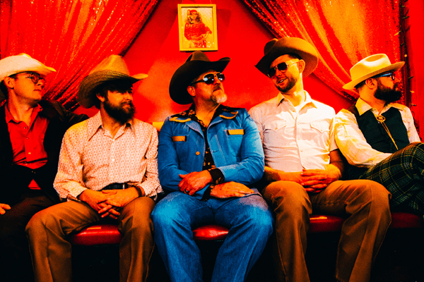 5 men sitting on a couch in cowboy hats