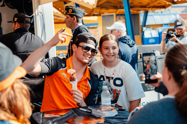 Racecar driver taking a photo with a young fan
