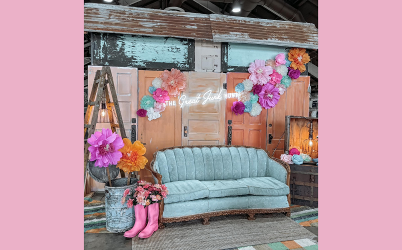 A blue couch with doors and flowers behind it with a sign saying "The Great Junk Hunt".